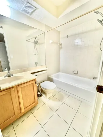 Guest Bathroom featuring washtub / shower combination, vanity, light tile patterned floors, and a textured ceiling