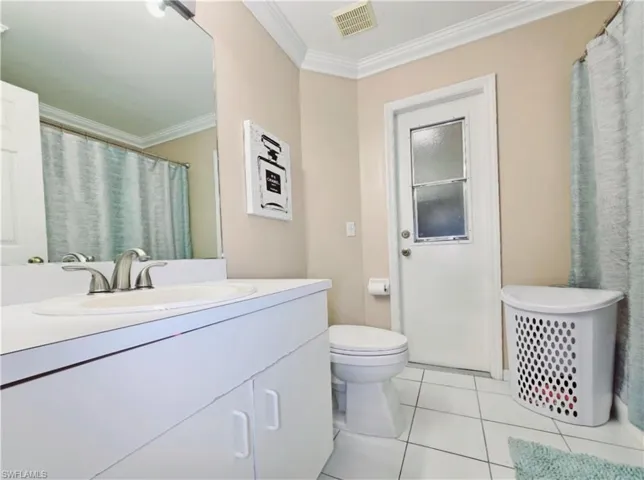 Guest Bathroom with tile patterned floors, vanity, toilet, Shower/Tub, ornamental molding and door to the porch