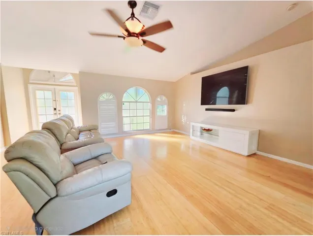 Living room featuring french doors, natural light, hardwood / wood-style floors, and vaulted ceiling