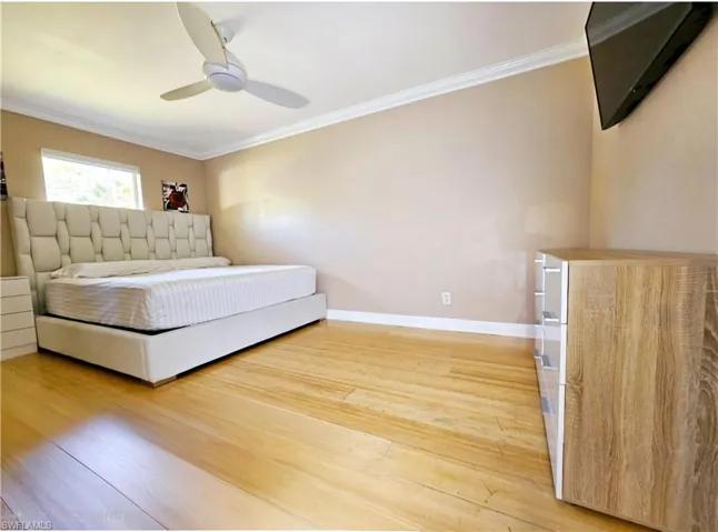 Second bedroom with hardwood / wood-style flooring, ceiling fan, and crown molding