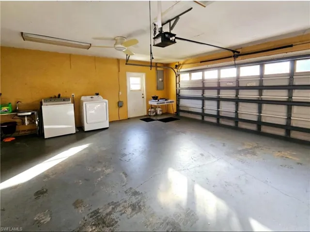 Garage featuring washer / dryer, electric panel, a garage door opener, and ceiling fan