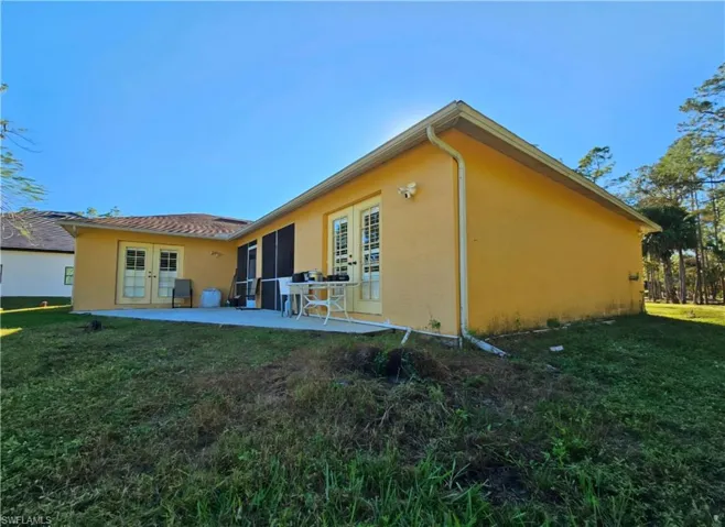 Rear view of house with a yard, a patio area, and french doors