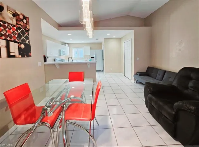 Tiled dining room featuring sink and vaulted ceiling