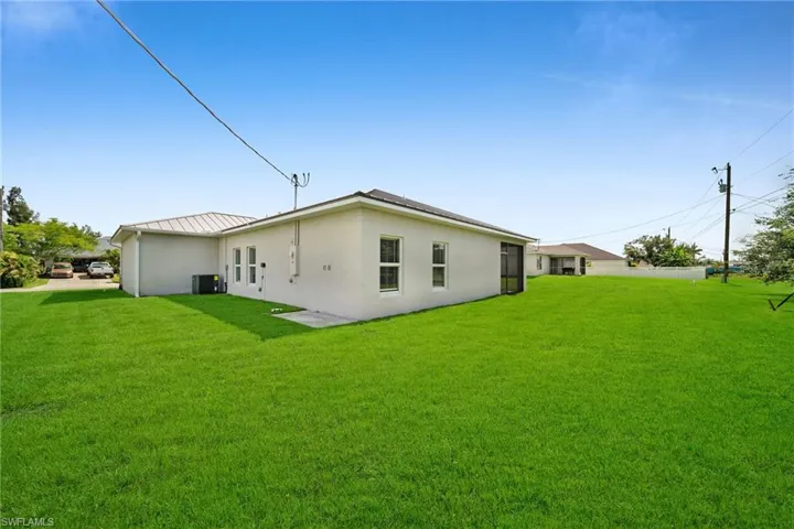 Back of property featuring cooling unit and a lawn
