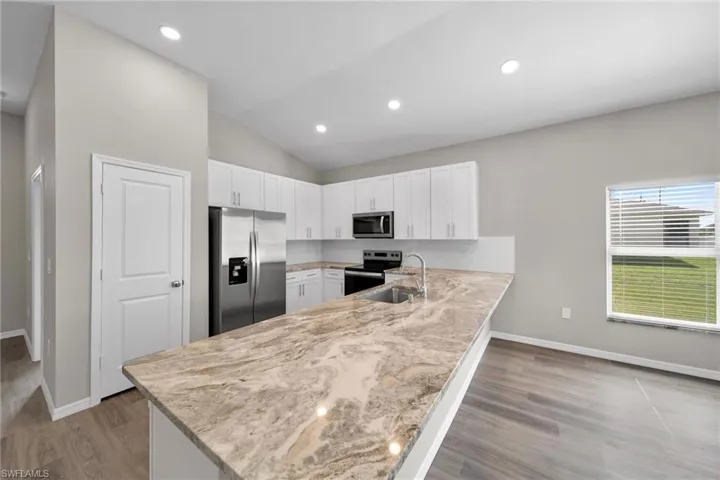Kitchen featuring white cabinetry, stainless steel appliances, kitchen peninsula, and light hardwood / wood-style floors