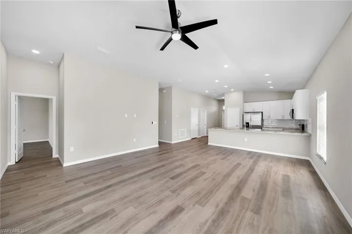 Unfurnished living room featuring high vaulted ceiling, light wood-type flooring, and ceiling fan