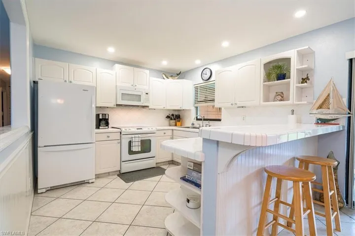 Kitchen with white cabinets, tile floor, breakfast bar