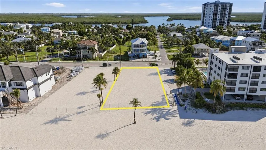 Beachfront lot with established palm trees, bordered by a paved road, and proximate to water features - Virtually Edited Image