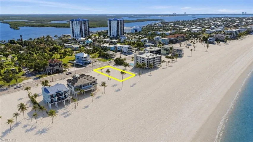 Beachfront property featuring a sandy expanse, palm trees, and water frontage - Virtually Edited Image