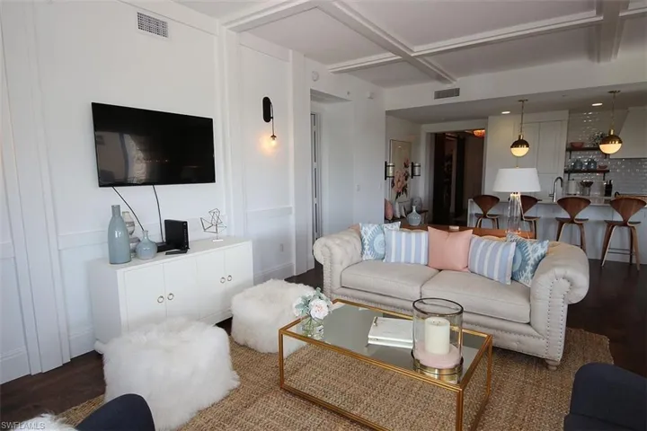 Living room with wood finished floors, coffered ceiling, and beamed ceiling