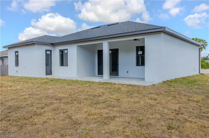 Rear view of property featuring fence, a patio, a lawn, and stucco siding