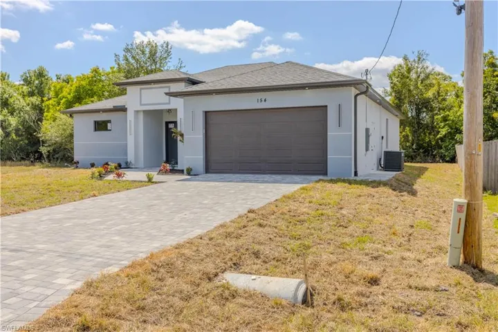 View of front of house featuring a front yard, a garage, stucco siding, decorative driveway, and roof with shingles