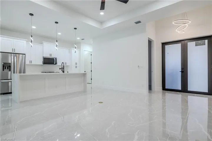 Living area with baseboards, a ceiling fan, recessed lighting, french doors, and marble finish floor