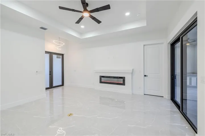 Unfurnished living room featuring a glass covered fireplace, baseboards, recessed lighting, a ceiling fan, and marble finish floor