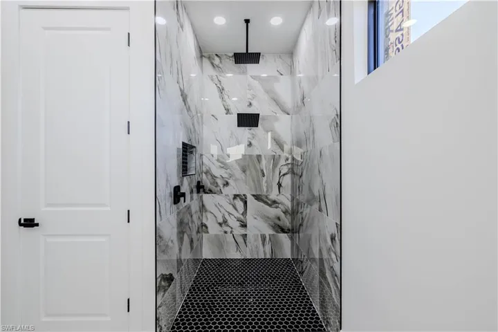 Bathroom with a marble finish shower and recessed lighting