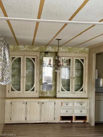 Detailed view of wood tiled floors, a chandelier, a textured ceiling, and wooden walls