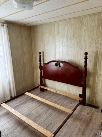 Unfurnished bedroom with wood finished floors, wood walls, and a textured ceiling
