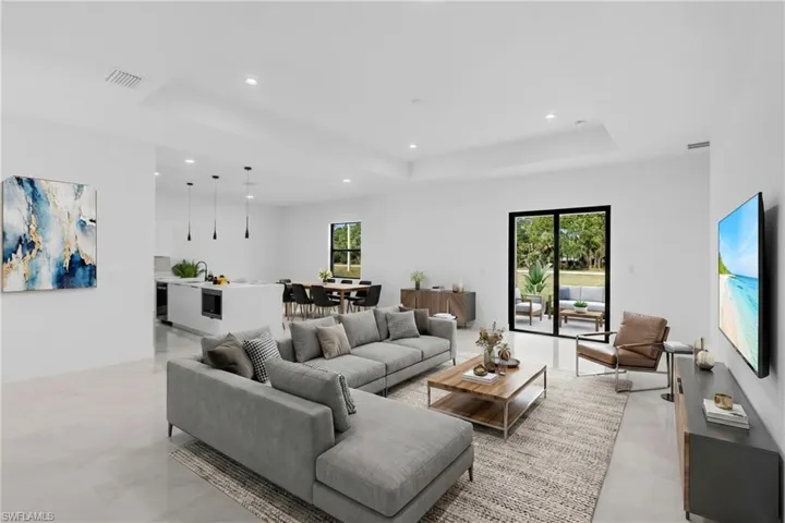 Open-concept living space featuring a tray ceiling, recessed lighting, tile flooring, and sliding glass doors to the exterior