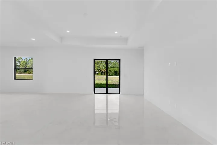 Expansive room featuring light-toned large format tile flooring, a tray ceiling, and recessed lighting