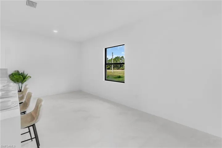 Spacious room featuring white walls, white tile flooring, recessed lighting, and a single window with black trim