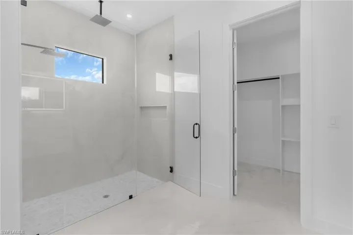 Walk-in shower with full-height glass enclosure, dual rain shower heads, recessed niche, and horizontal window