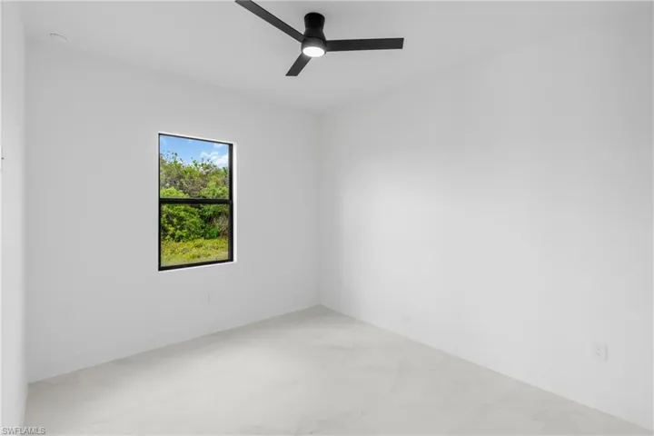 Bright interior room featuring a single window with black trim, a black ceiling fan with integrated lighting, recessed ceiling lighting, and light-colored tile flooring