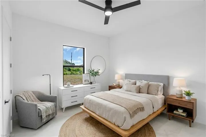 Virtually Staged.  Bright bedroom with a modern ceiling fan, white walls, and a large window offering natural scenery