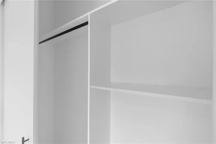 Built-in closet system featuring white shelving, hanging rod, and white paneling