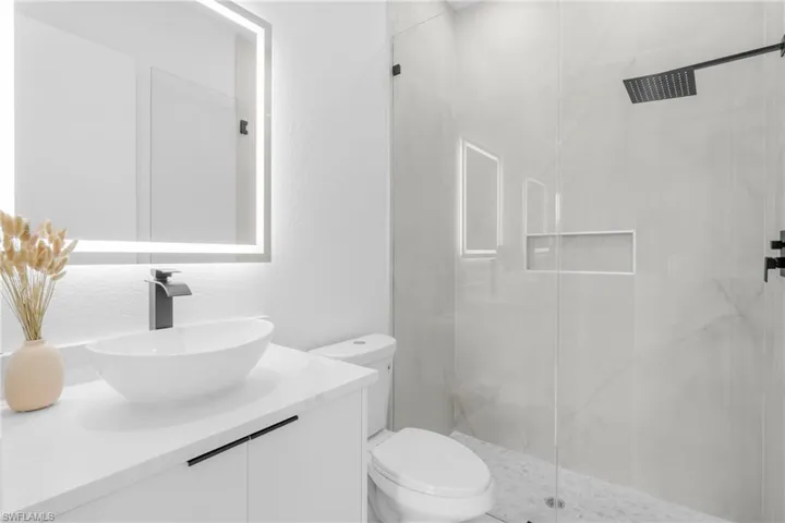 Contemporary bathroom featuring a floating vanity with a vessel sink, an illuminated mirror, and matte black hardware