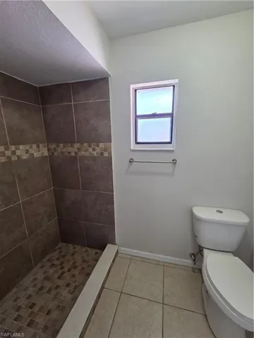 Bathroom with a shower stall and light tile patterned floors