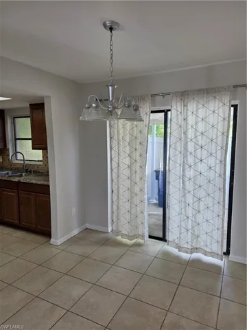 Unfurnished dining area with hanging lights and light tile patterned flooring