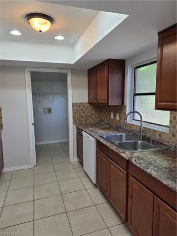 Kitchen featuring light tile patterned flooring, dishwasher, backsplash, recessed lighting, and dark stone countertops
