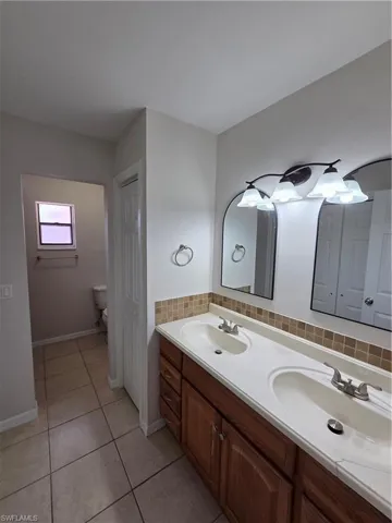Bathroom featuring double vanity, tasteful backsplash, and light tile patterned flooring