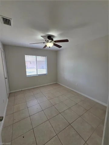 Empty room featuring light tile patterned floors and a ceiling fan
