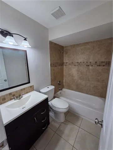 Full bathroom featuring vanity, bathtub / shower combination, light tile patterned floors, and backsplash