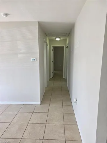 Hallway with light tile patterned floors and baseboards