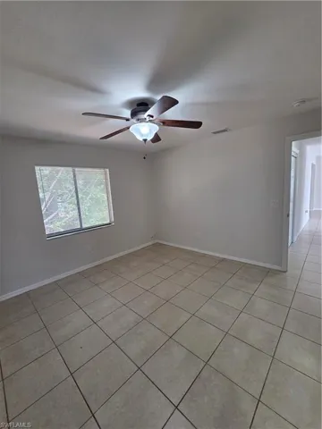 Empty room with light tile patterned floors and a ceiling fan