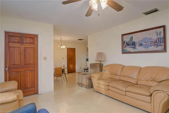 Living room with ceiling fan with notable chandelier and light hardwood / wood-style flooring
