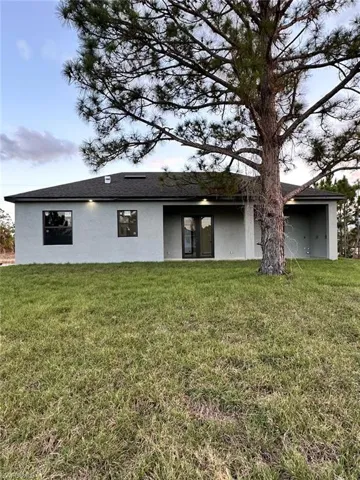 Rear view of house with stucco siding and a yard