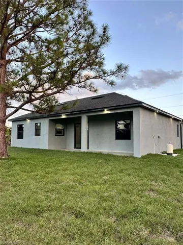 Back of house featuring stucco siding, a yard, a patio area, and roof with shingles