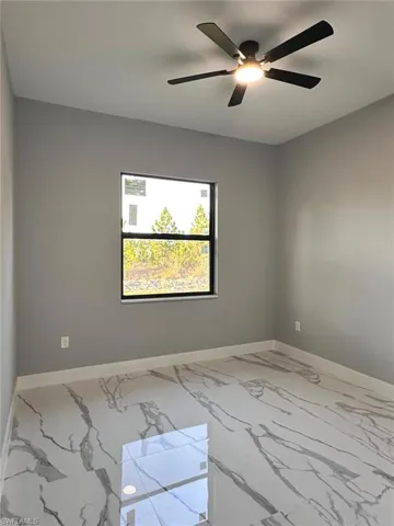 Empty room featuring baseboards and ceiling fan