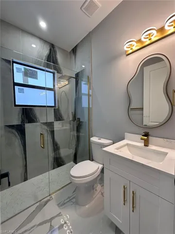 Full bath with vanity, a marble finish shower, and marble finish flooring