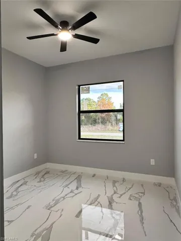 Spare room with light marble finish floors and a ceiling fan