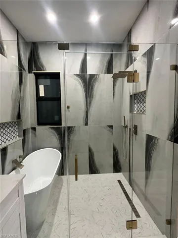 Bathroom featuring a marble finish shower and a freestanding tub