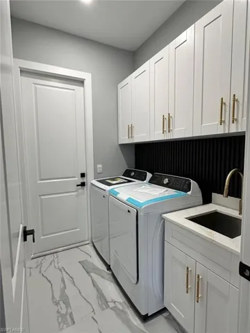 Laundry room with cabinet space, separate washer and dryer, and light marble finish flooring