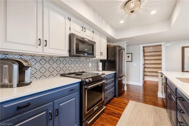Kitchen with blue cabinets, white cabinetry, stainless steel appliances, and dark hardwood / wood-style floors