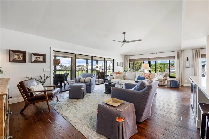 Living room with dark wood-type flooring, vaulted ceiling, and ceiling fan