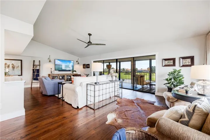 Living room with ceiling fan, lofted ceiling, and dark hardwood  floors