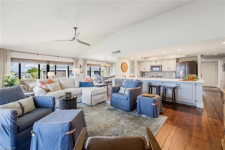 Living room with vaulted ceiling, ceiling fan and dark hardwood wood flooring