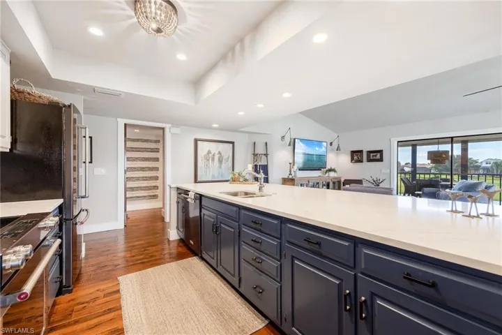 Kitchen featuring hardwood flooring, a tray ceiling, stainless steel appliances, sink, and quartz countertops